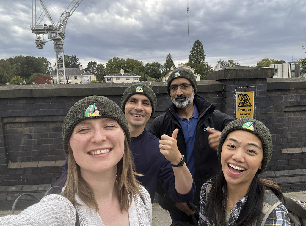 Four smiling Trailmix teammates in matching Trailmix beanies, mid-selfie on a city street during the Values Hunt.